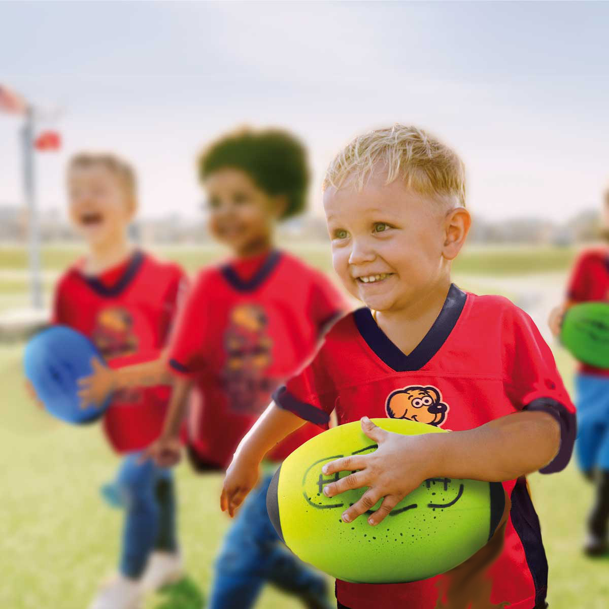 Children running and carrying footballs in a FootballTots class