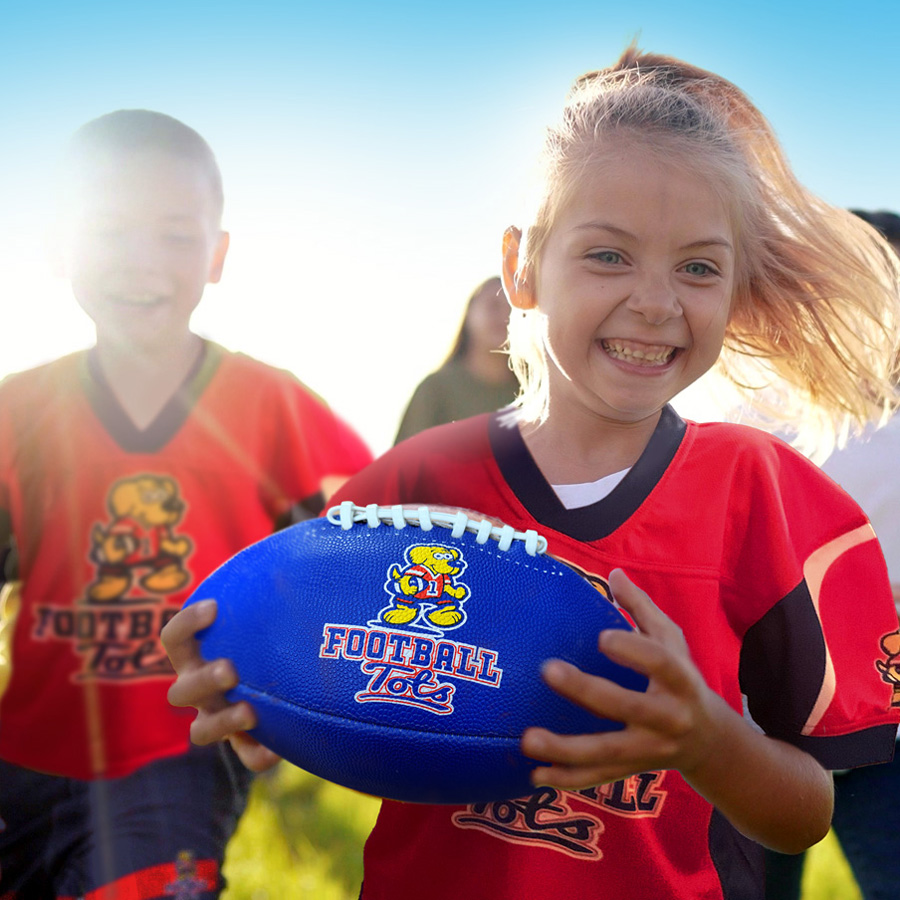 Girl running with a football at a FootballTots class